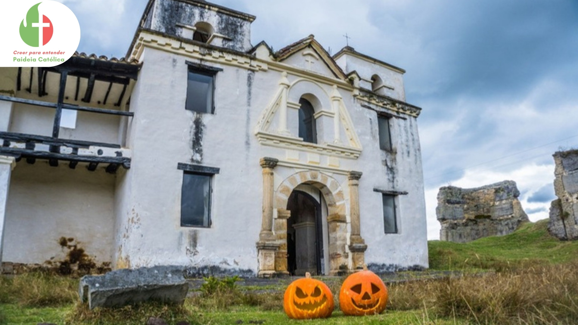 Iglesia colonial blanca con dos calabazas de Halloween frente a la puerta